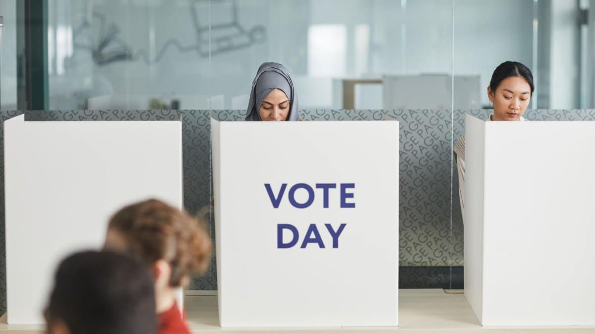 Two women casting their votes in an office during election day, focusing on diversity and civic engagement.