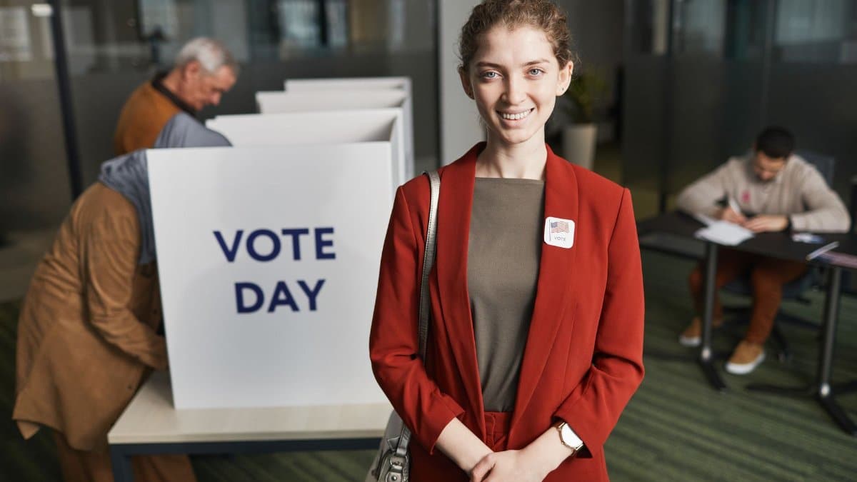 Woman in red suit at voting station, promoting civic engagement on election day.