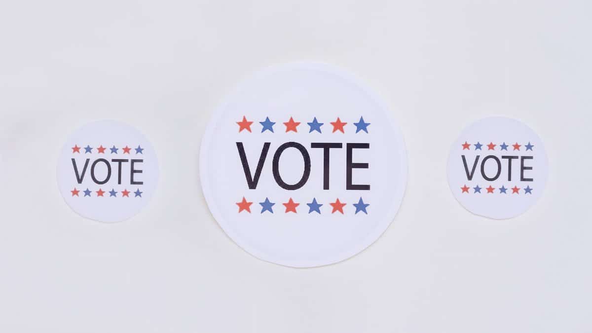 Three vote stickers featuring stars symbolize political participation on a white surface.