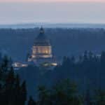 Dramatic view of the Washington State Capitol building in Olympia at dusk, surrounded by forest.