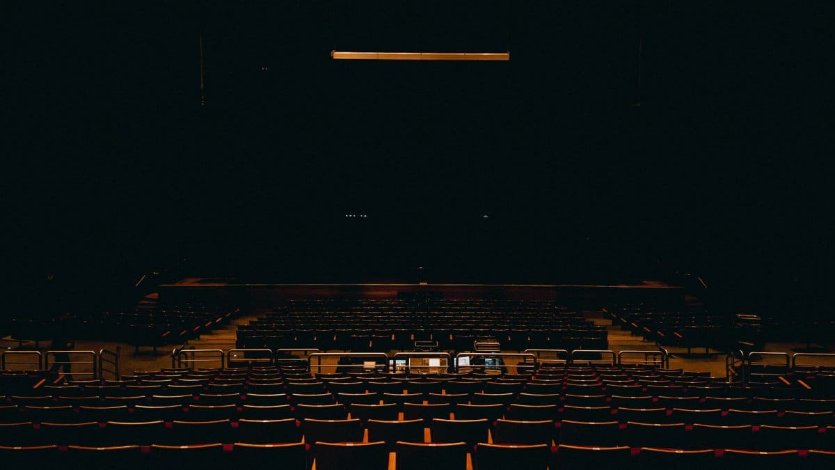 A dark and empty auditorium in Fortaleza, featuring rows of chairs and a stage.