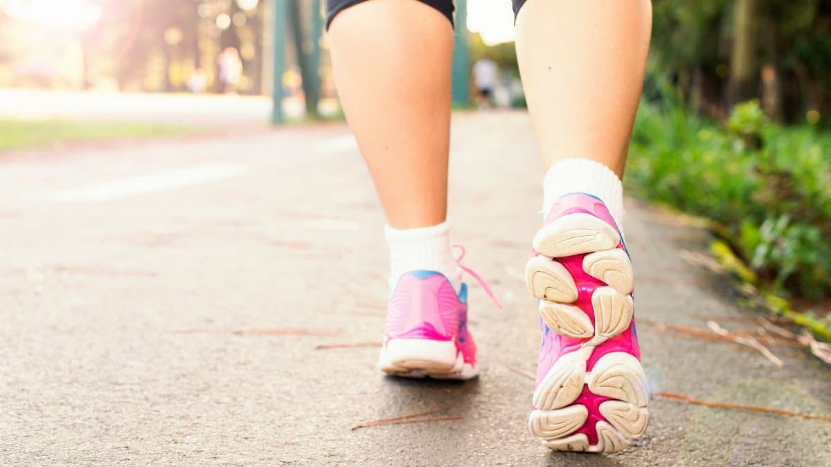 Close-up of a woman walking on a path in pink sneakers, embracing fitness and an active lifestyle.