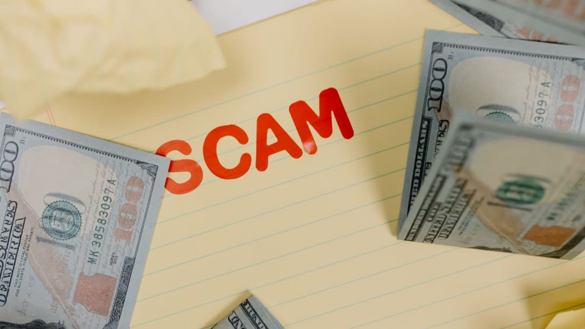 Conceptual image of financial scam with US dollars on yellow paper and word 'scam' visible.