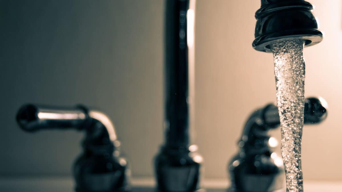 A detailed shot of water flowing from a steel faucet, ideal for themes on cleanliness or plumbing.