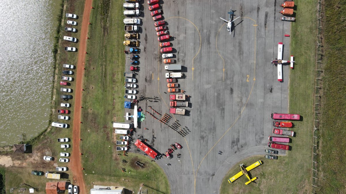 Aerial view of assembled firefighting vehicles and equipment at an outdoor event, showcasing organized emergency response preparation.