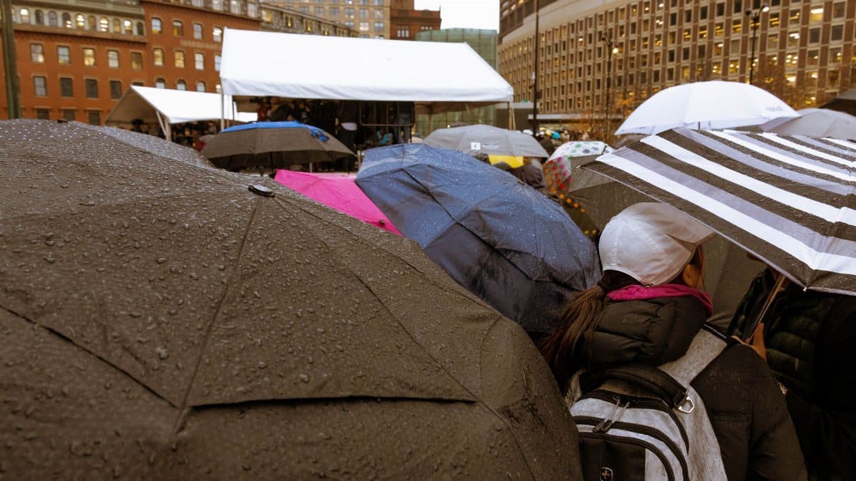 Crowd with umbrellas in a rainy Boston square, showcasing urban weather scene.