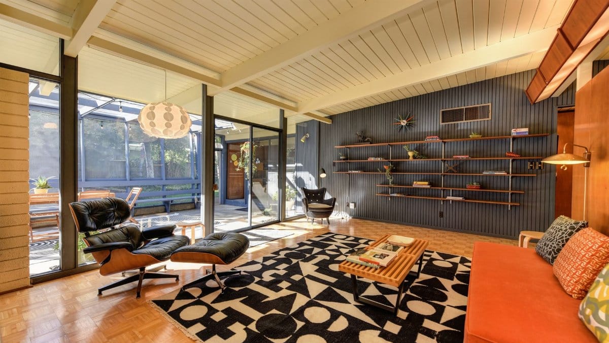 Stylish mid-century modern living room with armchairs, shelves, and natural light.