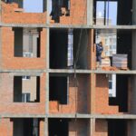 View of construction workers building brick walls on an unfinished urban apartment.