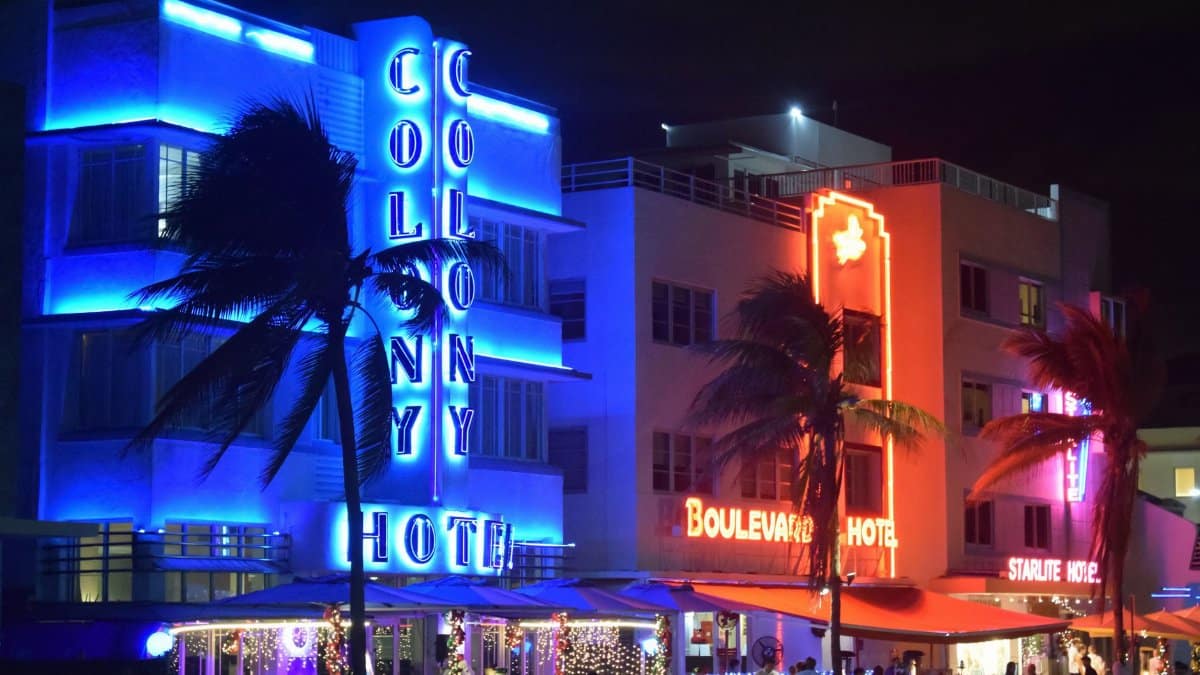 Lively neon-lit hotels illuminate the Miami Beach nightlife, highlighting Art Deco architecture.