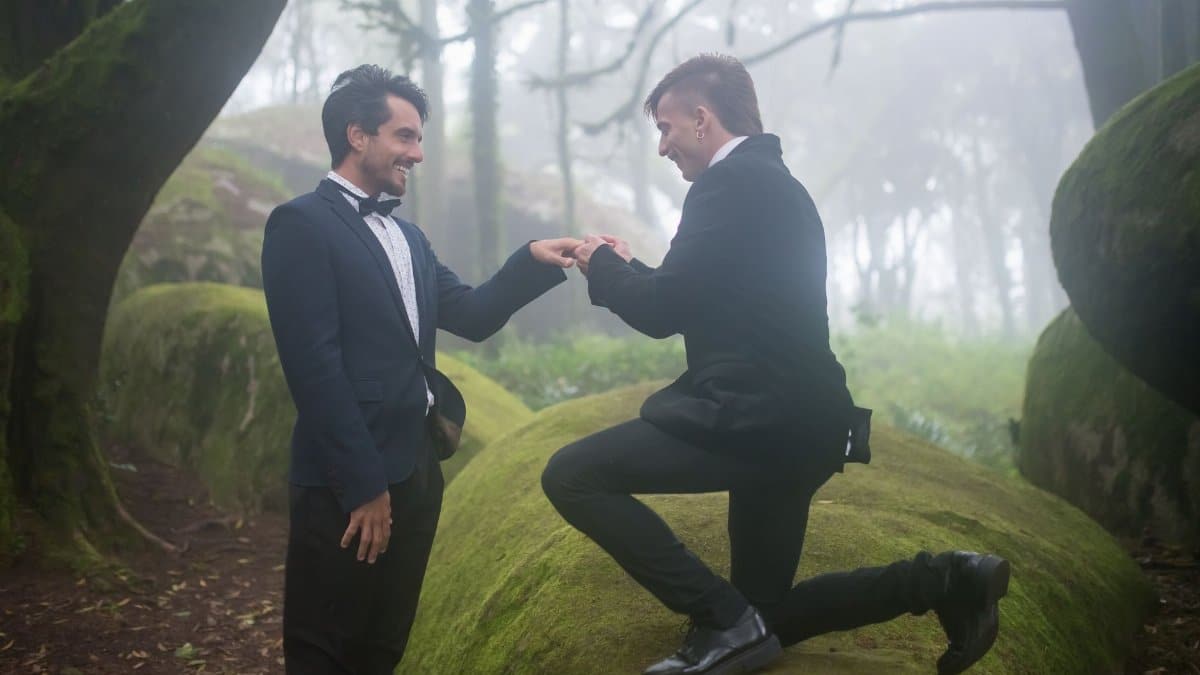 A joyous same-sex proposal amidst the serene and foggy forest landscape in Portugal.