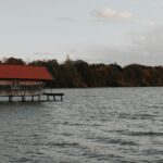 Charming wooden boathouse on Ammersee Lake in Bavaria, framed by a serene autumn landscape.