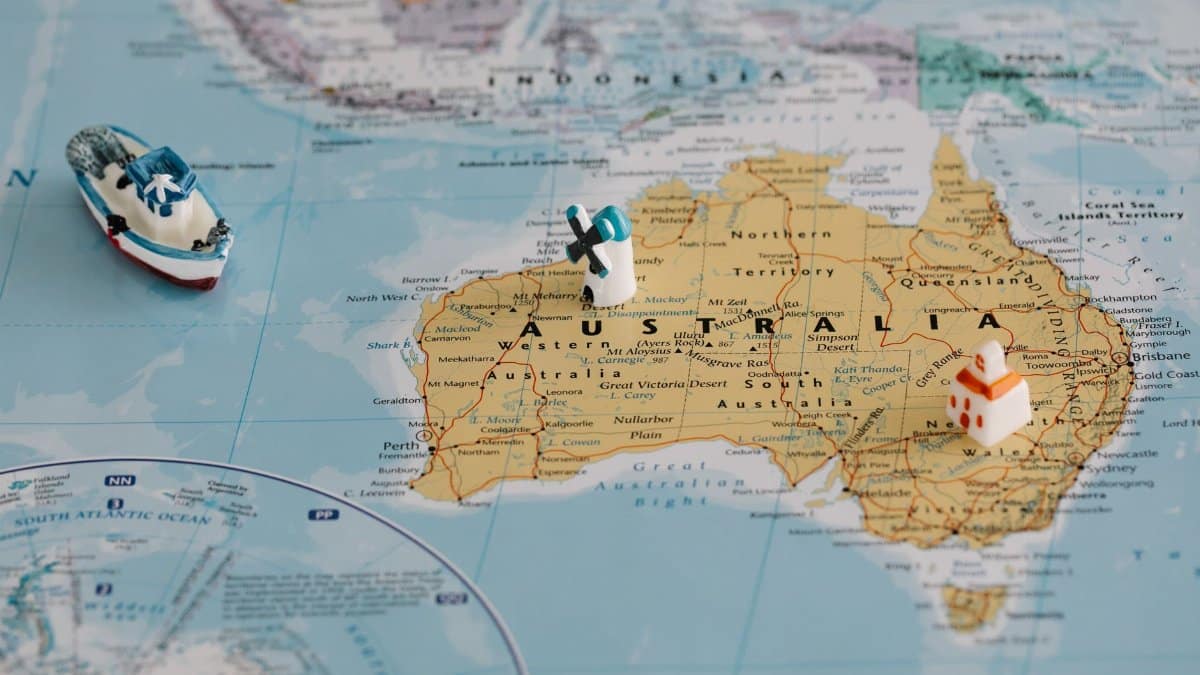 Miniature windmill and ship placed atop a map of Australia, highlighting travel concepts.