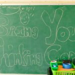 Classroom scene with chalkboard message "Bring Your Thinking Cap" and supplies.
