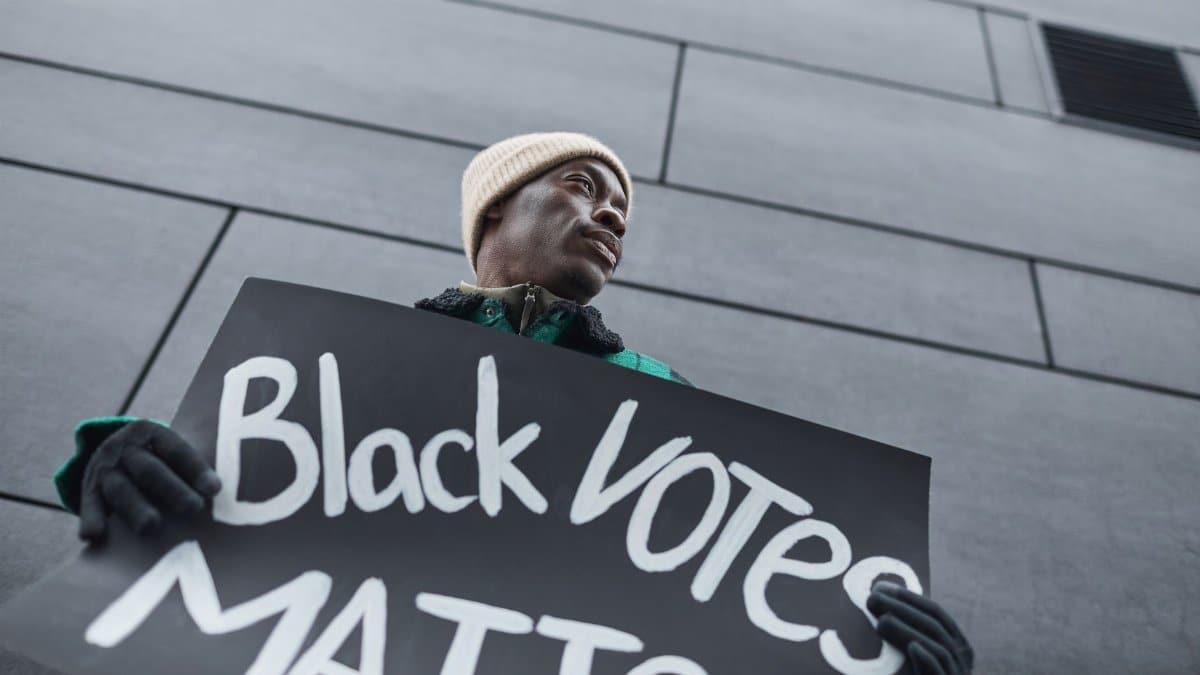 Low-angle shot of an activist holding a Black Votes Matter placard during a protest.