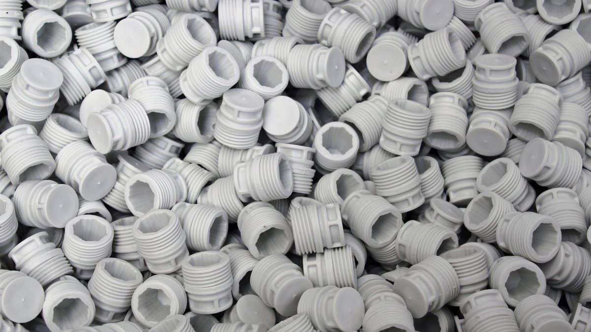 A high-quality image of numerous white plastic screw caps piled together, showcasing industry production.