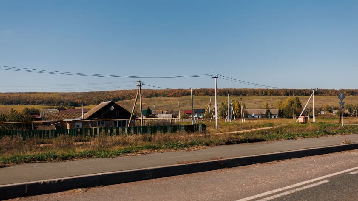 Tranquil rural landscape with fields and power lines under a clear blue sky.