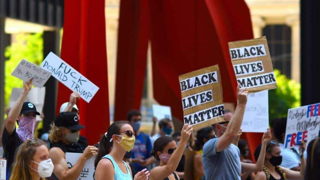 Protesters gather with signs supporting Black Lives Matter and denouncing Donald Trump in a peaceful rally.