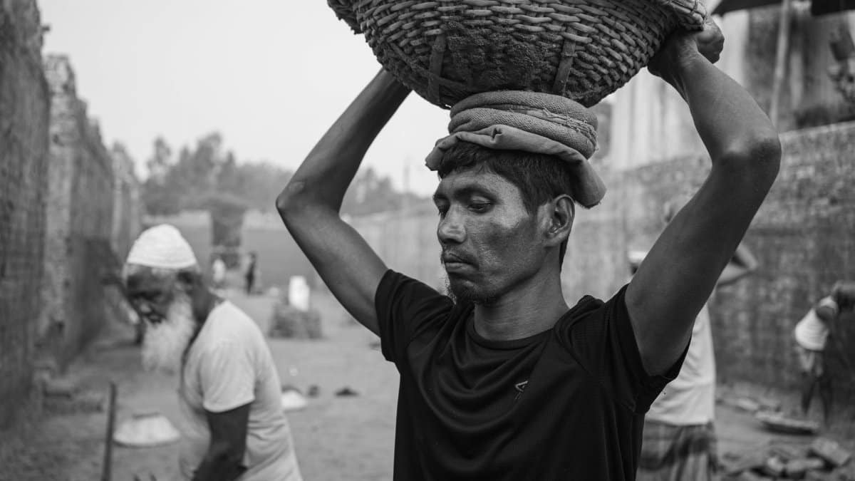 A black and white photo of workers in a brick field in Dhaka, showcasing labor and working conditions.