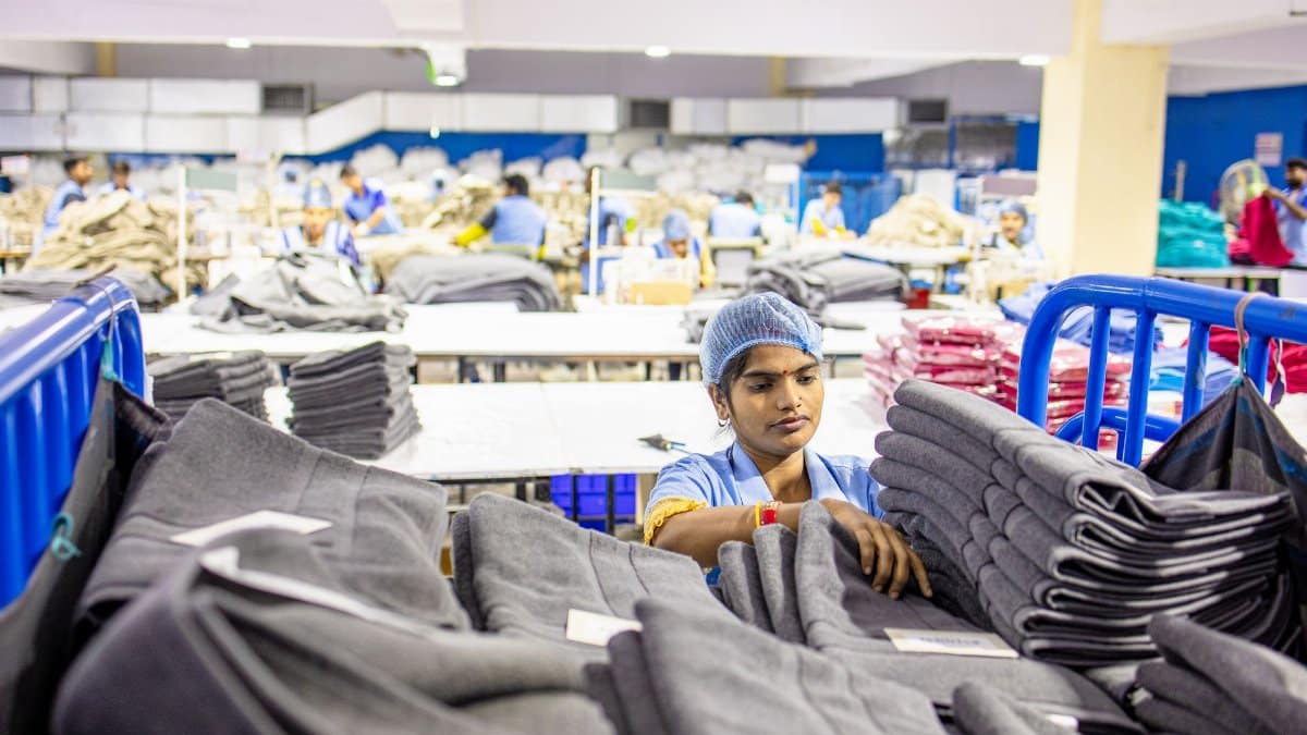 Textile worker sorting fabric piles in a busy South Asian apparel factory.