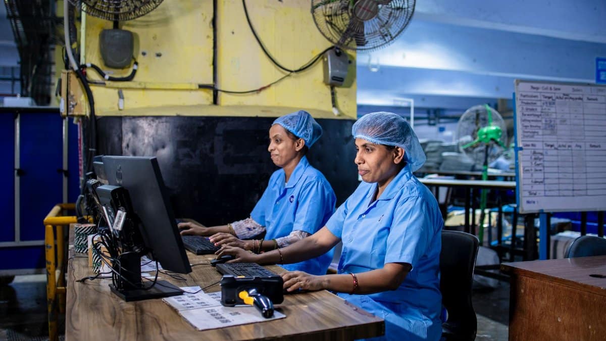 Two female textile workers using computers in a factory setting.