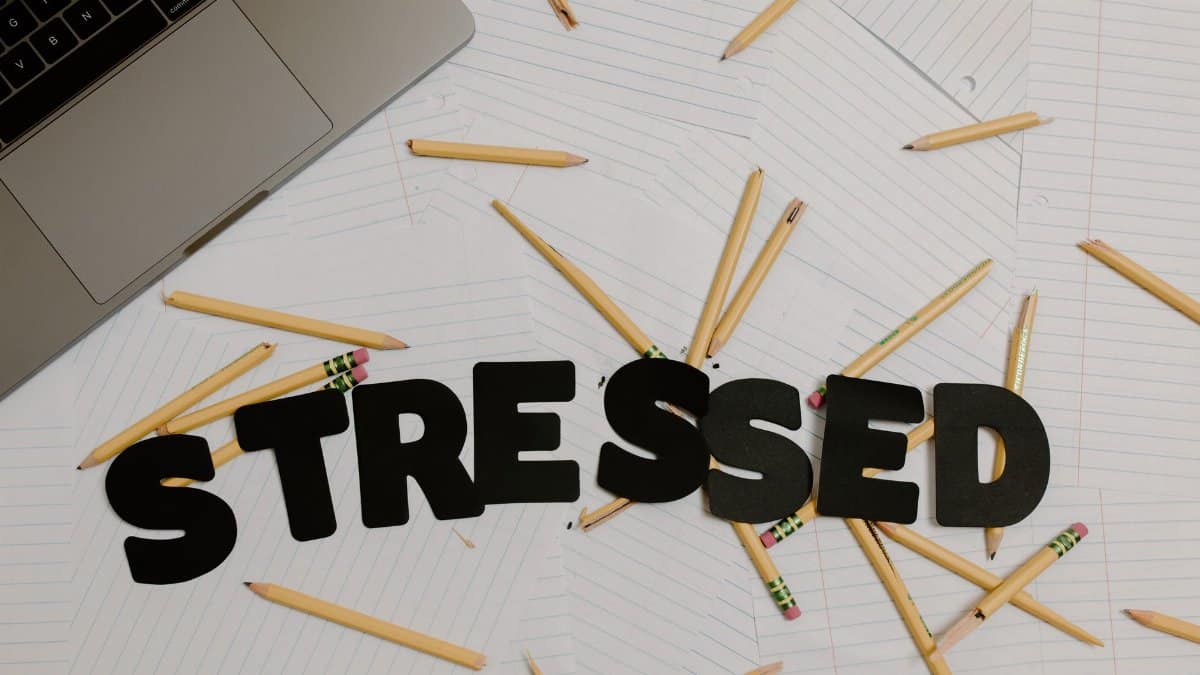 Overhead view of a stressed workplace setup with broken pencils scattered around a laptop.