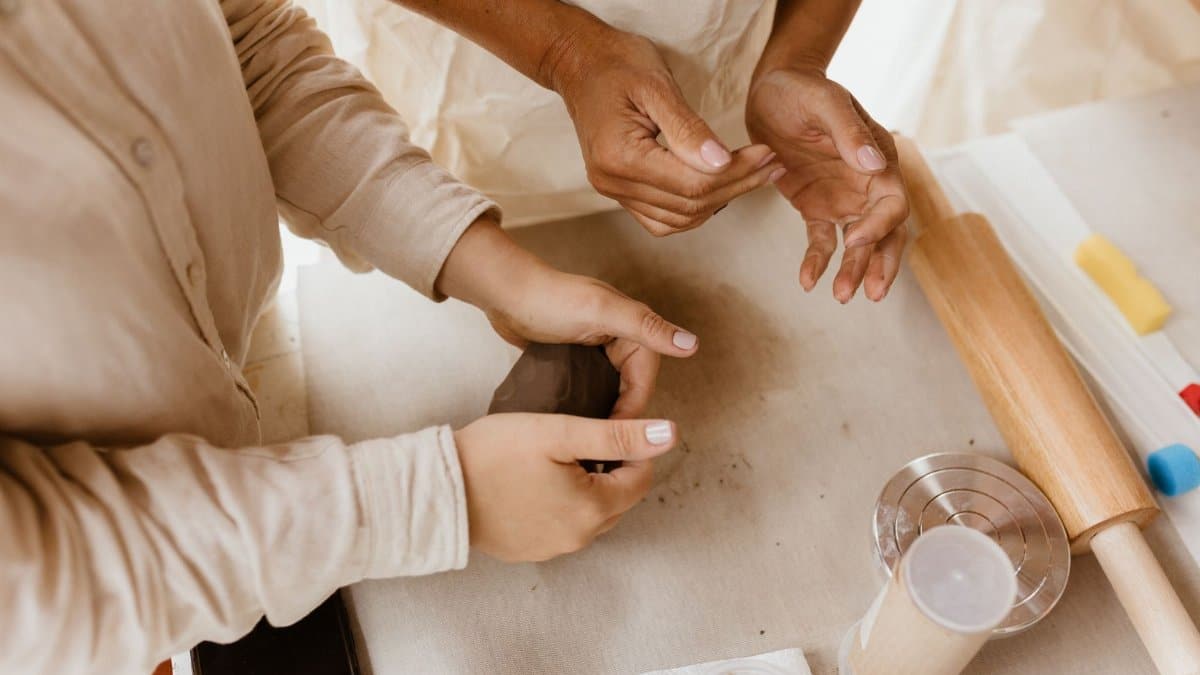 Close-up of hands engaged in molding clay, showcasing artisan skills with rolling pin and crafting tools.