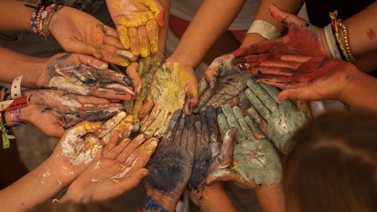 A close-up of a group showing painted hands in vibrant colors symbolizing unity and creativity.