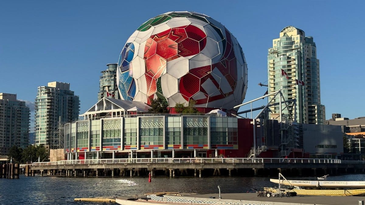 A massive soccer ball decorates Science World, set against Vancouver's iconic skyline and waterscape.