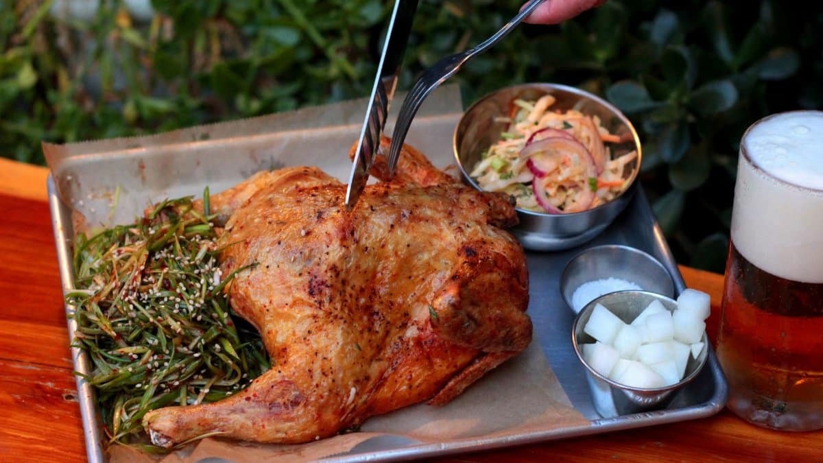 A delicious roasted chicken served with sides and a refreshing beer, captured outdoors.