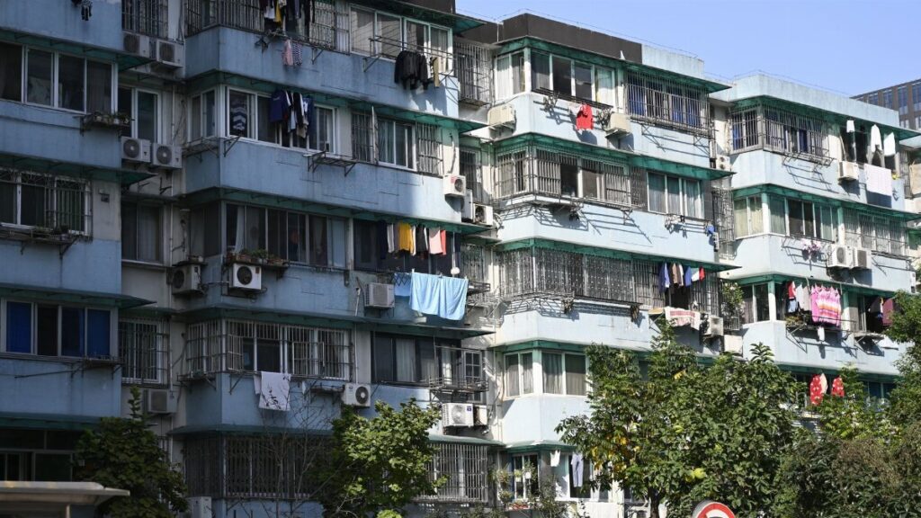 Exterior view of urban apartments with laundry hanging outside on balconies under a clear sky.