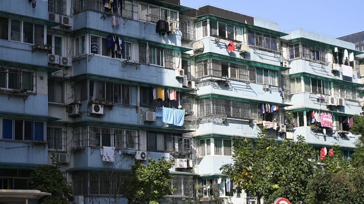Exterior view of urban apartments with laundry hanging outside on balconies under a clear sky.