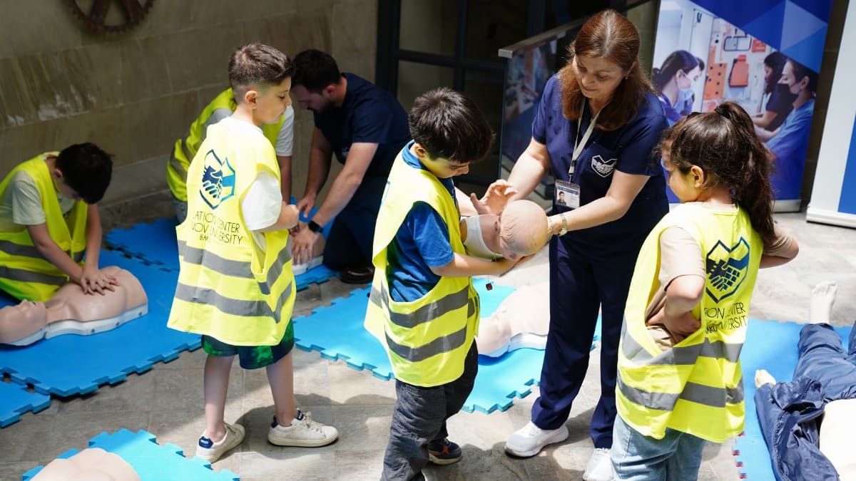 Kids learning CPR skills in an educational safety workshop indoors led by instructor.