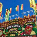 Vibrant fair stand in Grapevine, TX with corn dogs, lemonade, and flags under clear skies.