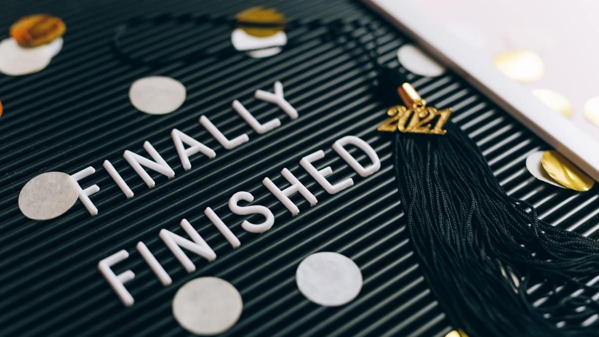 Close-up of 'Finally Finished' sign with graduation tassel and 2021 charm on letter board.