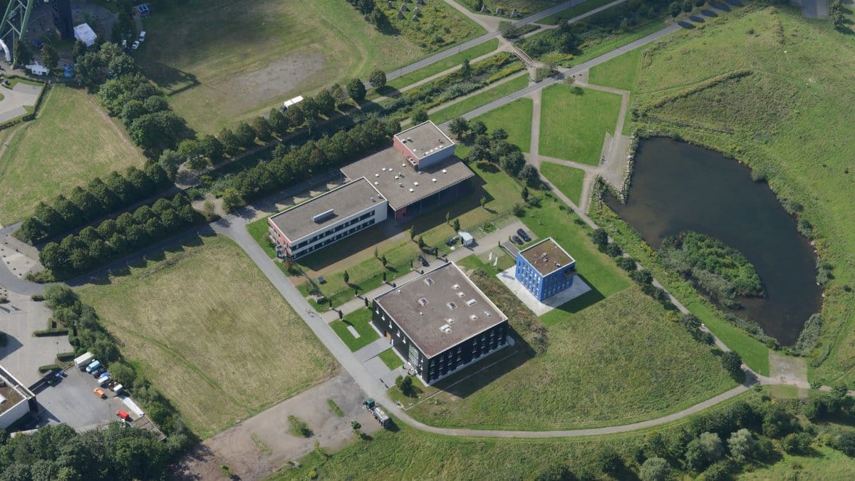 A stunning aerial photograph showcasing a modern educational campus with green landscapes and pathways, captured from above.