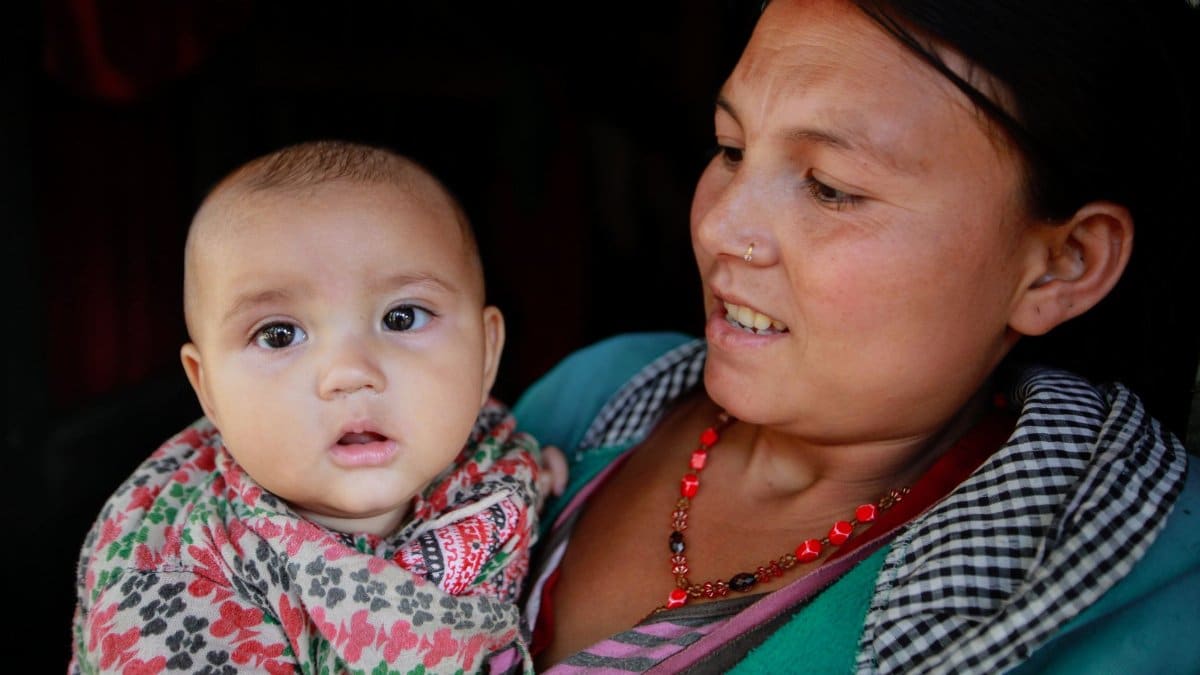 A mother lovingly holds her baby, capturing a tender moment between parent and child.