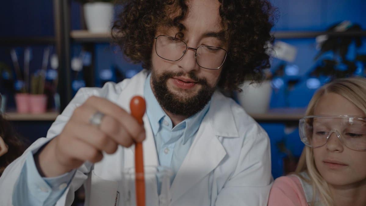 Bearded teacher and student exploring chemistry with lab equipment. Focus on learning and education.