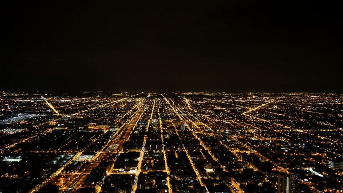 A breathtaking aerial view of a sprawling city illuminated by glowing lights against the night sky.