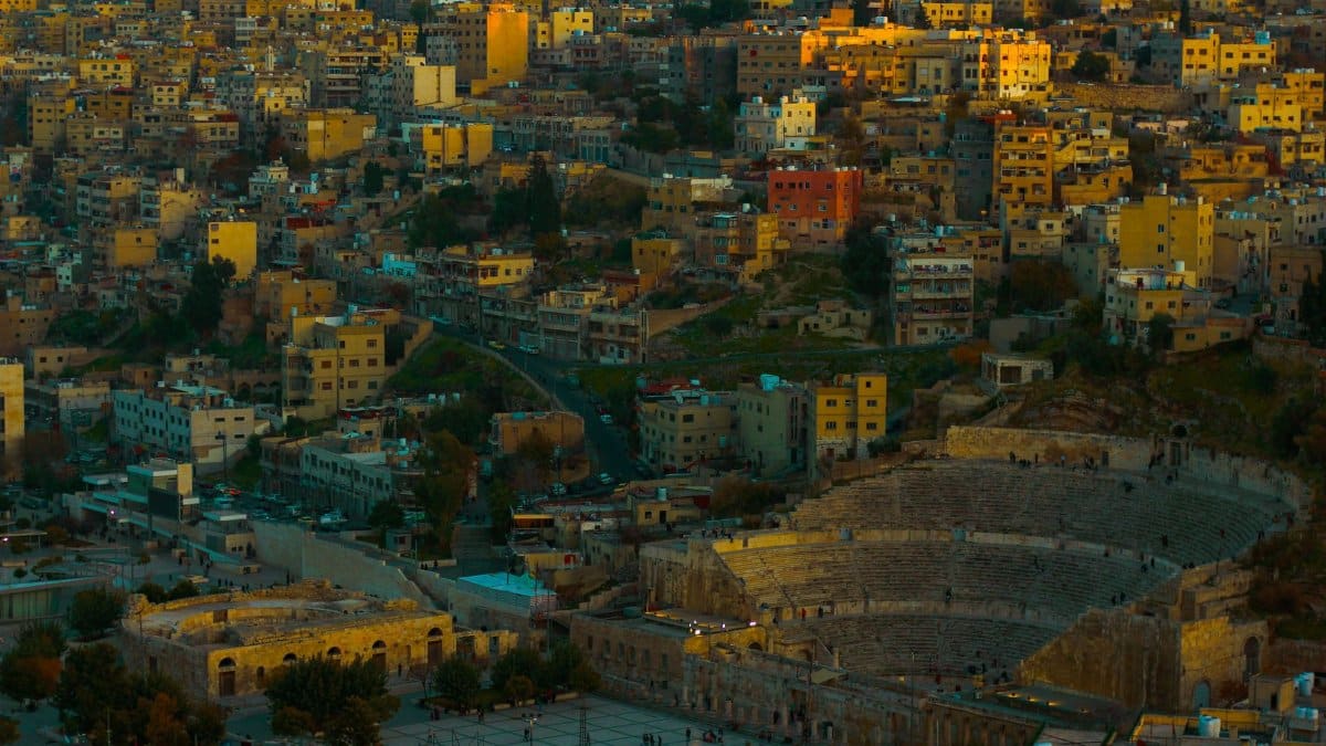 Sweeping aerial view of Amman city and iconic Roman Theatre at twilight.