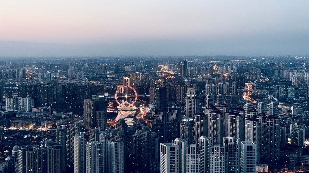 Stunning aerial cityscape view at dusk featuring a prominent ferris wheel and illuminated buildings.