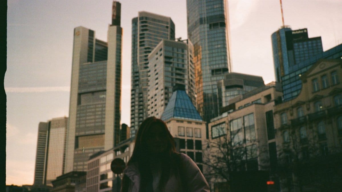 A silhouette of a person standing against a modern city skyline at sunset, creating a dramatic urban scene.