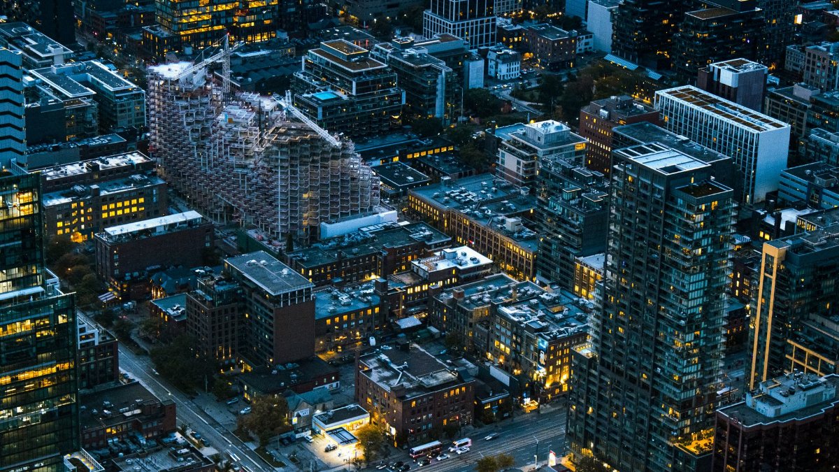Aerial view of Toronto's urban skyline at twilight, featuring tall buildings and city lights.