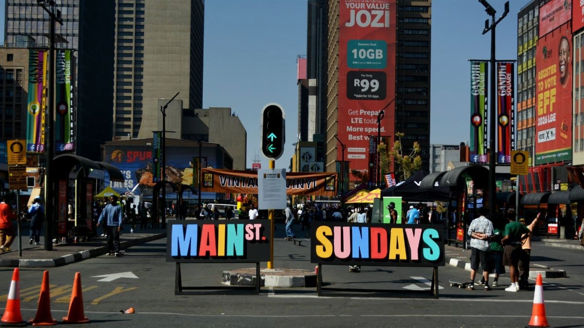 Vibrant urban street scene at Main St Sundays with crowds and colorful signage under the city skyline.