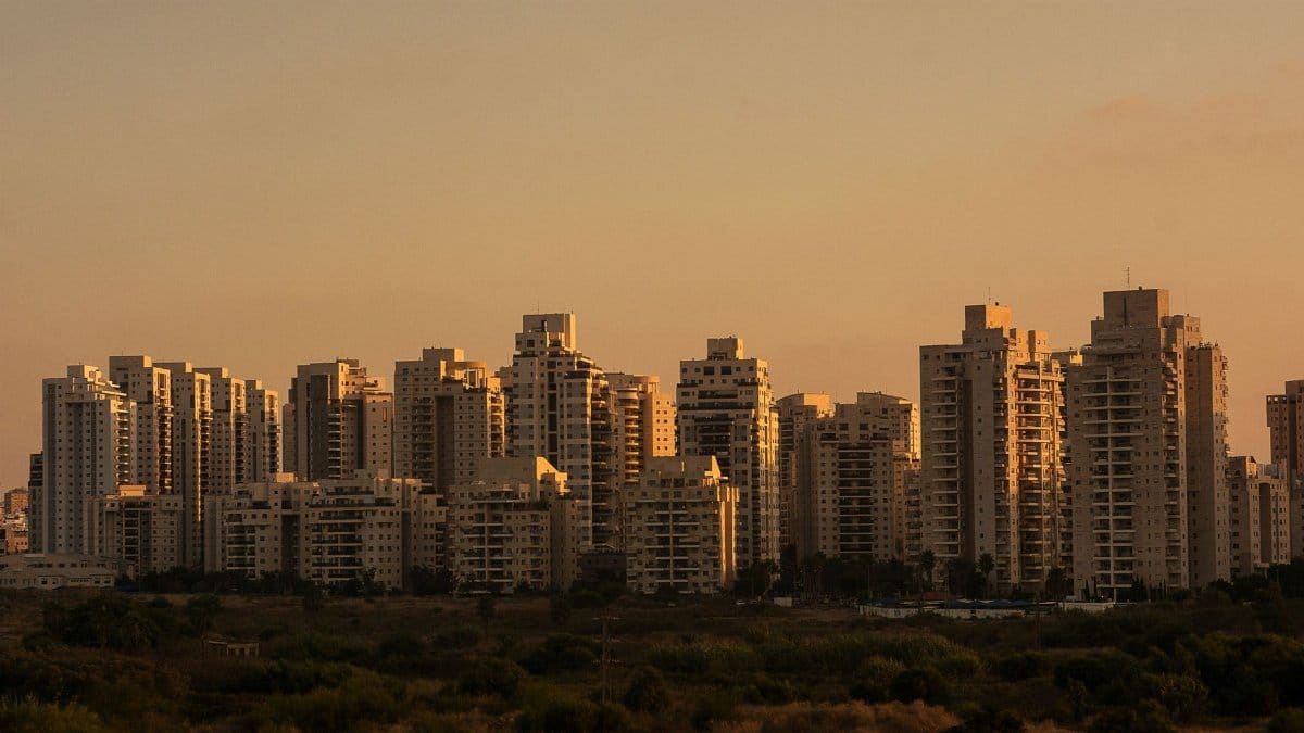 City skyline with tall skyscrapers silhouetted against a sunset sky.