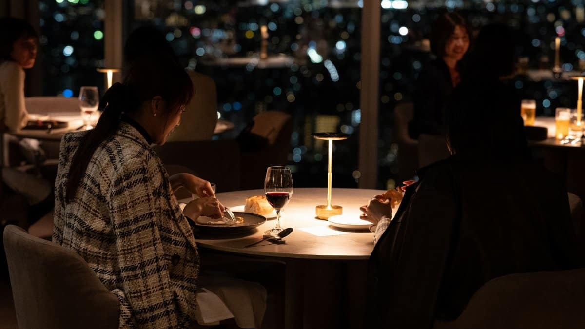 Sophisticated dinner setting in a Tokyo restaurant with city skyline view at night.