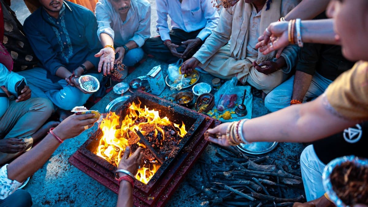 Group of Indian people performing a traditional Hindu ritual around a sacred fire.