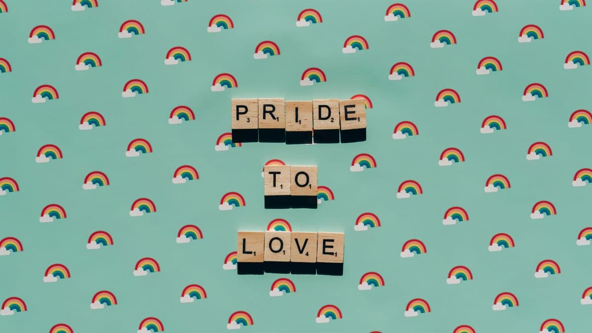 Scrabble tiles spelling 'Pride to Love' on a rainbow background, celebrating LGBT pride.