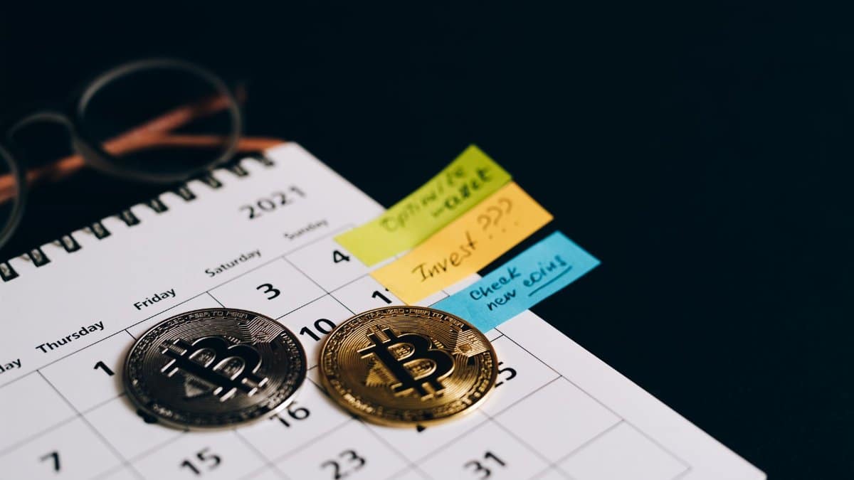 Bitcoin coins placed on a calendar with sticky notes for investment planning.