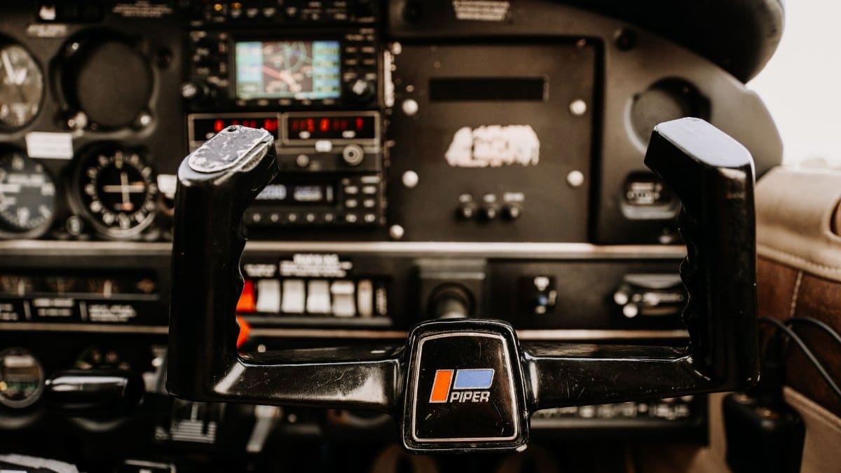 Detailed image of an aircraft cockpit showing controls and instrumentation inside a Piper plane.