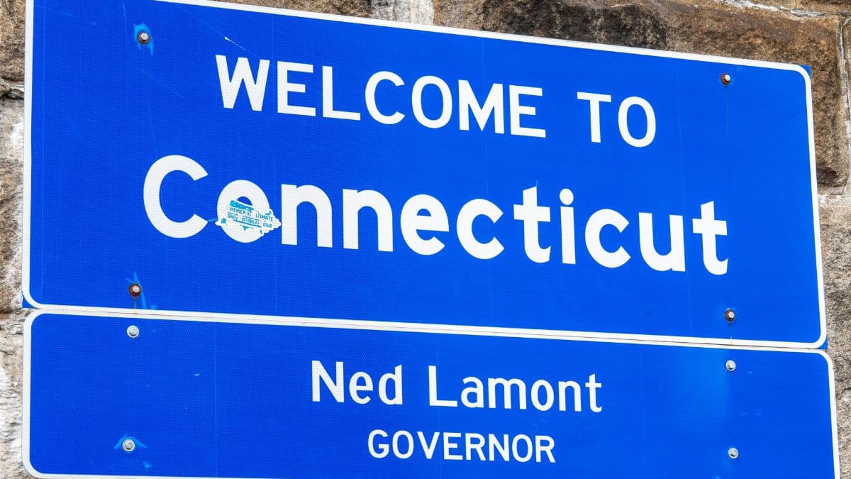 Close-up of a 'Welcome to Connecticut' sign with governor's name displayed, symbolizing state entrance.